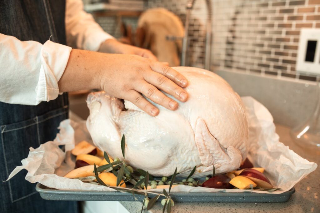 Person Holding Raw Turkey on a Baking Tray